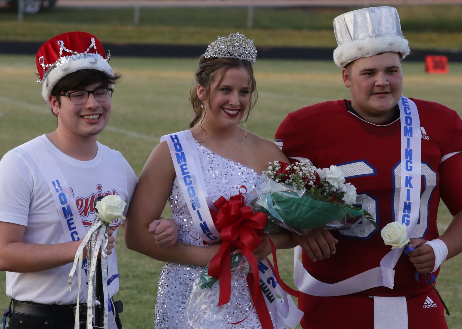 The 2022 Alba-Golden homecoming queen, Skyler West, is escorted by co-Kings Kevin Inman (left) and Eli Nivison prior to Friday’s football game.